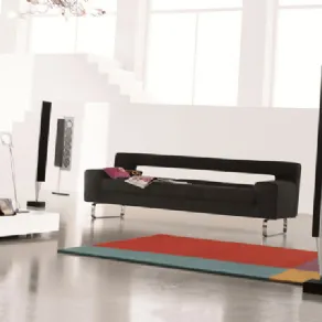 divano a tre posti nero con gambe in alluminio inserito in spazio living bianco con tappeto geometrico multicolore e casse verticali