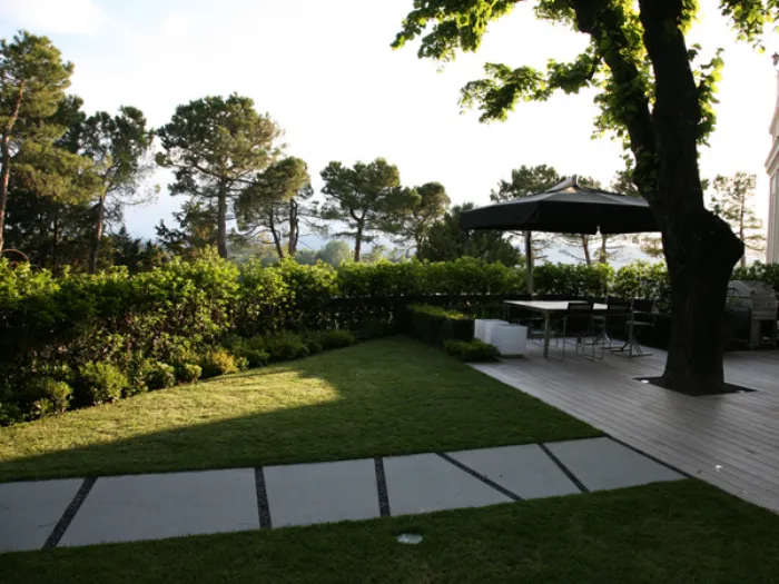 veduta di giardino con prato e pavimentazione a parquet, gazebo e tavola con sedie da esterno