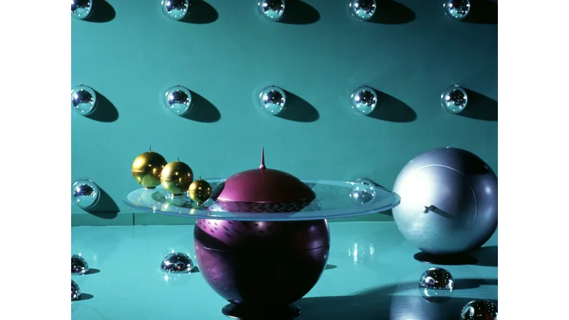 tavolino design: sfera viola con pannello circolare in vetro trasparente, tre sfere dorate, emisferi decorativi a parete
