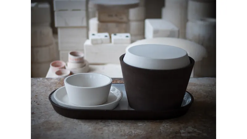 ciotola con sotto piatto in ceramica bianca, insalatiera in ceramica nera su vassoio in ceramica nero e bianco