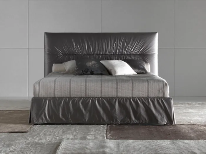 vista frontale del letto matrimoniale rivestito nei toni del grigio con lenzuola rigate