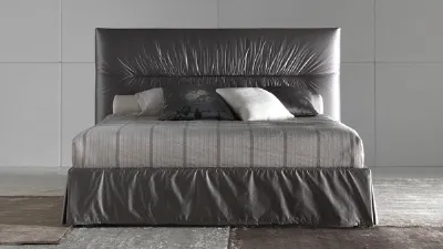 vista frontale del letto matrimoniale rivestito nei toni del grigio con lenzuola rigate