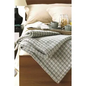 dettaglio di coperta ripiegato su bordo letto con vassoio in materiale organico per colazione