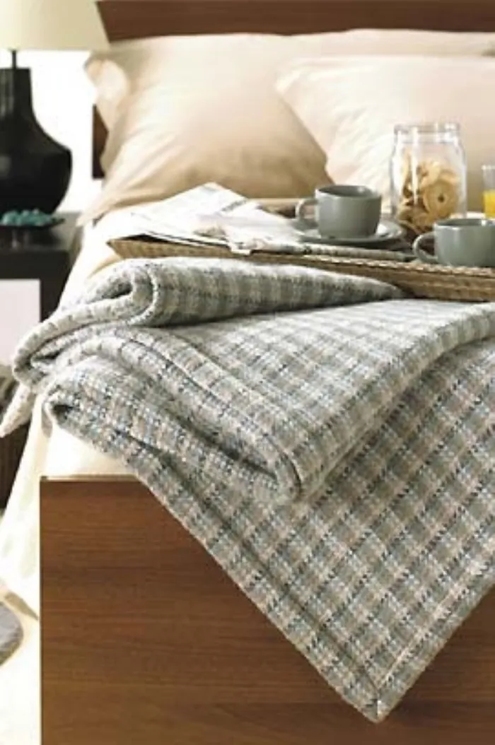 dettaglio di coperta ripiegato su bordo letto con vassoio in materiale organico per colazione