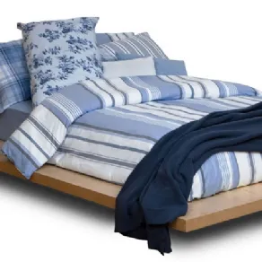 letto matrimoniale con copripiumino a righe sui toni dl blu e cuscini abbianti, coperta blu scuro