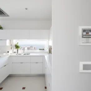 dettaglio di consolle di controllo su parete, vista su cucina bianca con finestra panoramica