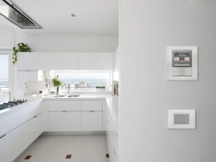 dettaglio di consolle di controllo su parete, vista su cucina bianca con finestra panoramica