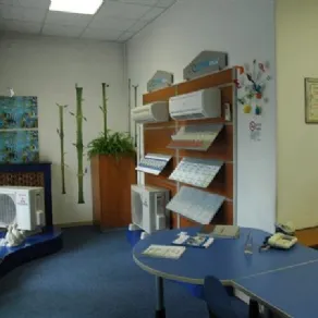 interno di negozio Climiamo con pavimento a moquette blu, tavolo blu ed espositore di climatizzatori in legno 