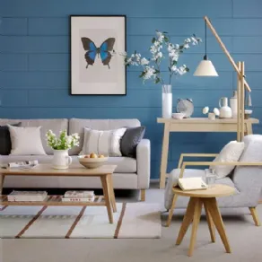 Divano e arredi di colore beige accostati ad un muri dipinto di azzurro intenso