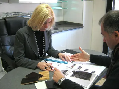 cliente e assistente scelgono la soluzione per la cucina attorno a un tavolo con catalogo