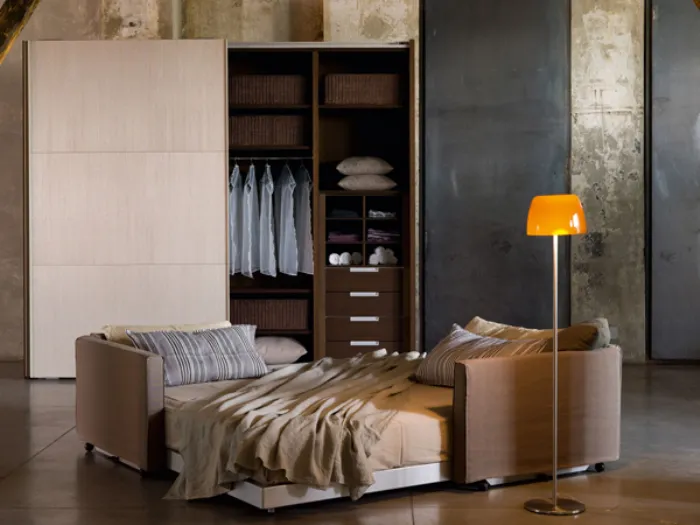 Camera da letto in stile essenziale con letto, lampada e armadio ad ante scorrevoli
