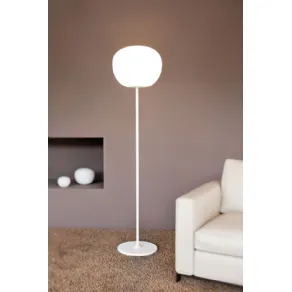 lampada da terra bianca con stelo verticale e paralume sferico, tappeto color naturale e poltrona bianca
