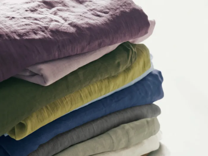 set di lenzuola piegate in lino nei colori melanzana, rosa, verde pino, verde chiaro, azzurro, blu e naturali