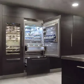 frigorifero incassato nell'armadiatura a muro con anta e cassettone aperti, cantina vini con anta trasparente