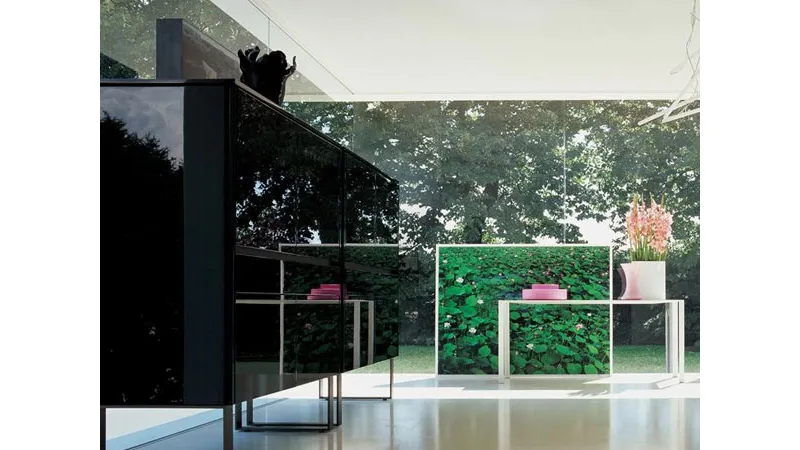 mobile da zona living in nero lucido, tavolino bianco con vaso bianco e fiori rosa, quadro con ninfee e parete vetrata