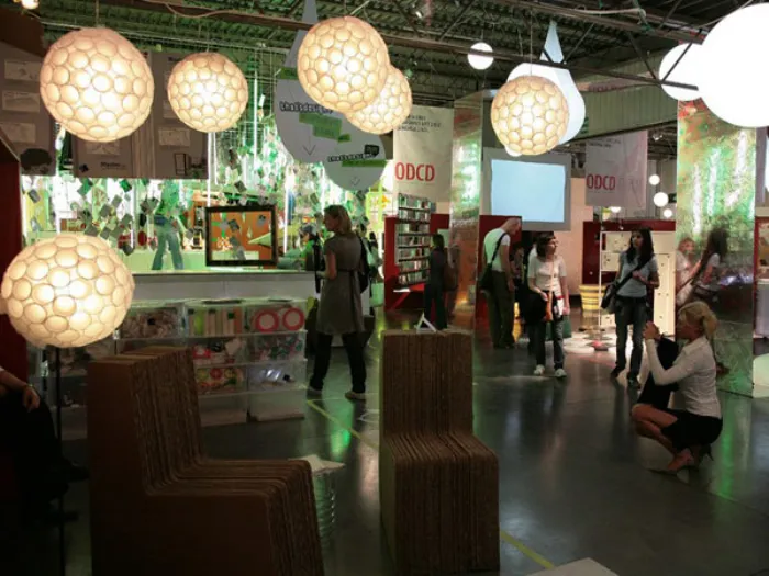stand espositivo con lampade sferiche e sedute in cartone, visitatori