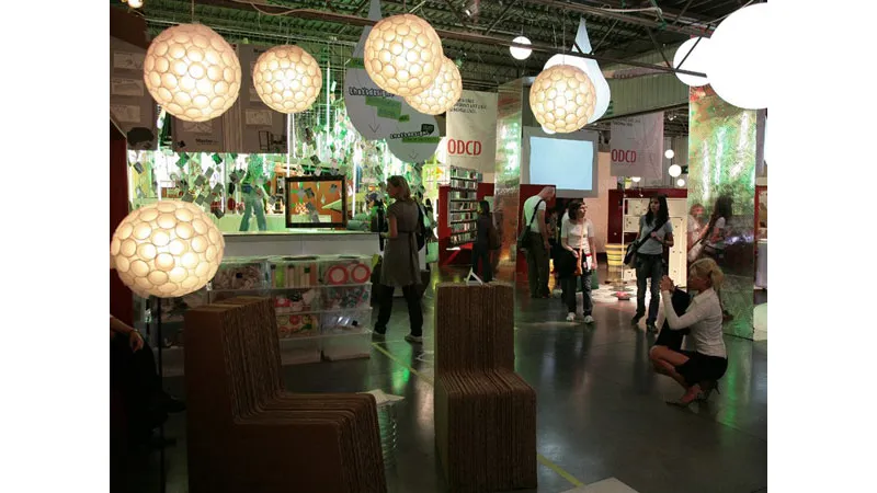 stand espositivo con lampade sferiche e sedute in cartone, visitatori