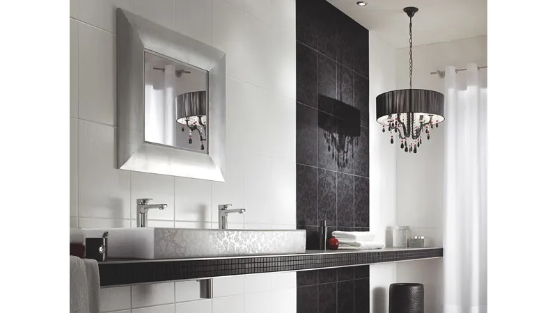 arredo bagno con piastrelle bianche e nere, lampadario con paralume circolare nero e gocce, specchio quadrato con cornice argentata