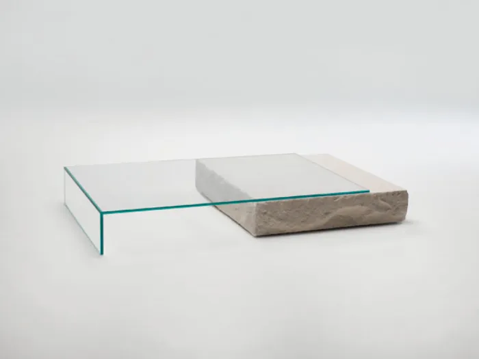 tavolino con piano in cristallo trasparente appoggiato su parallelepipedo in pietra