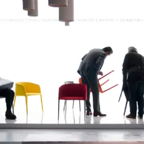 spazio espositivo con sedute multicolore e tre visitatori