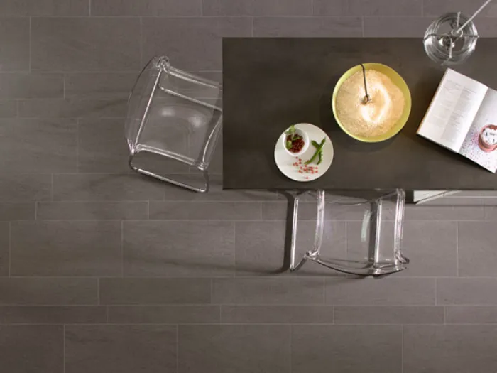vista dall'alto di tavolino con sedie trasparenti e pavimento a piastrelle rettangolari in gres porcellanato grigio