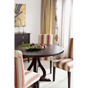 tavolino in legno scuro con frutta e tre sedie con schienale alto rivestite in tessuto a righe verticali bianco, bourdeaux, verde acido e verde oliva