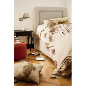 letto matrimoniale con tessili e cuscini color panna con fantasie floreali jacquard, pouf rosso