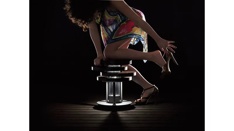 Donna che perde una scarpa vicino colonna luce a forma di sgabello