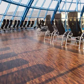 vista angolare di ampio spazio coperto da cupola vetrata con pavimento in legno multicolore e serie di sdraio nere