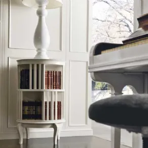 dettaglio boiserie e girello portalibri bianchi, abat-jour bianca e pianoforte in primo piano