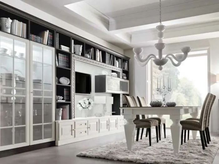 panoramica zona living: vetrina, libreria con spazio tv e cassettiera, tavolo bianco, sedie foderate e lampadario bianco