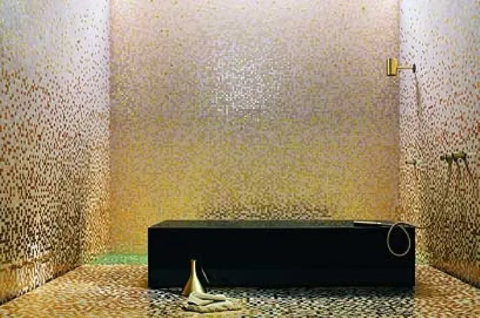 bagno con pareti e pavimento in mosaico dorato, vasca squadrata nera