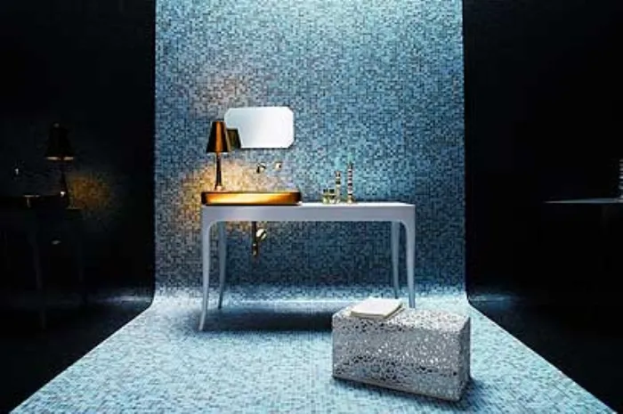 fascia di parete e pavimento a mosaico nelle tinte del blu con tavolino bianco, abat jour con lavabo dorati e puf in ferro battuto bianco
