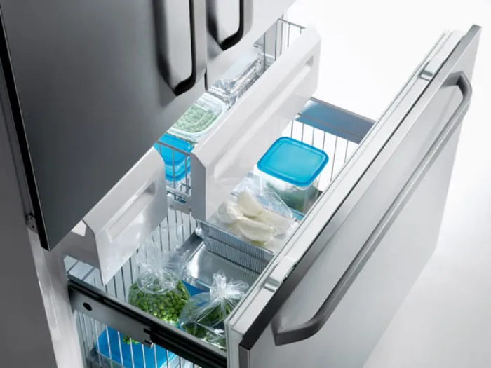 cassetto inferiore aperto di frigorifero a due ante con contenitori e scomparti