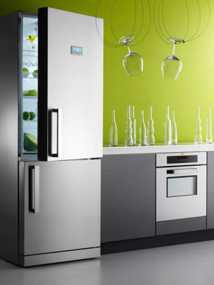 frigorifero con anta superiore aperta, parete verde mela, vasi trasparenti su ripiano e bicchieri trasparenti appesi a cavi pendenti