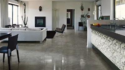 cucina e zona living con penisola con piano nero e parete rivestita a mosaico, pavimento a piastrelle di marmo, divano bianco e camino