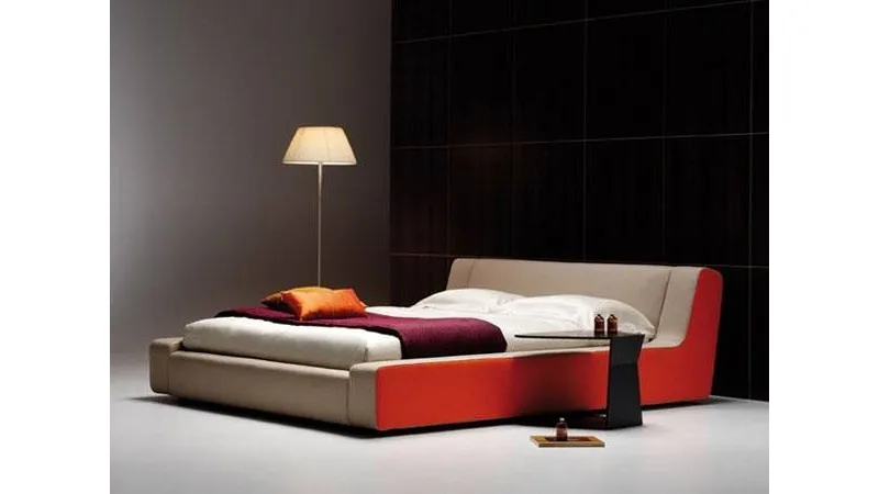 letto matrimoniale con struttura nelle tinte beige e mattone, tavolino nero e lampada da terra con paralume