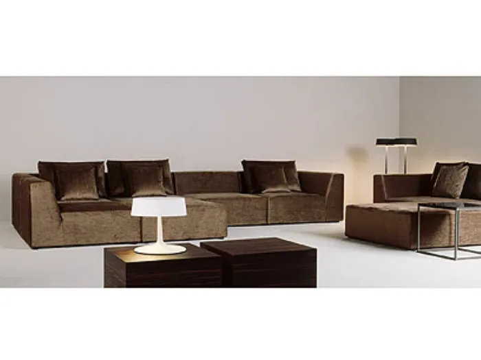 stand espositivo con sistema di divani in velluto marrone, tavolino in legno con lampada bianca