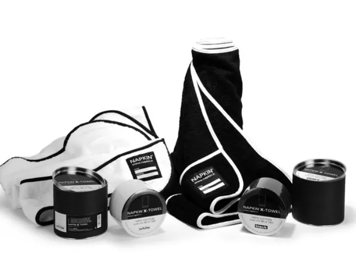 due asciugamani nero e bianco con bordi a contrasto, quattro contenitori cilindrici bianchi e neri