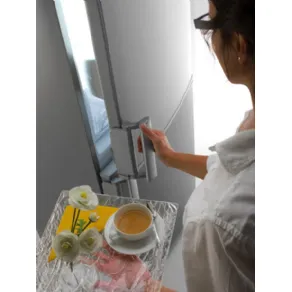 donna con vassoio con tè e fiori apre l'anta superiore del frigo 
