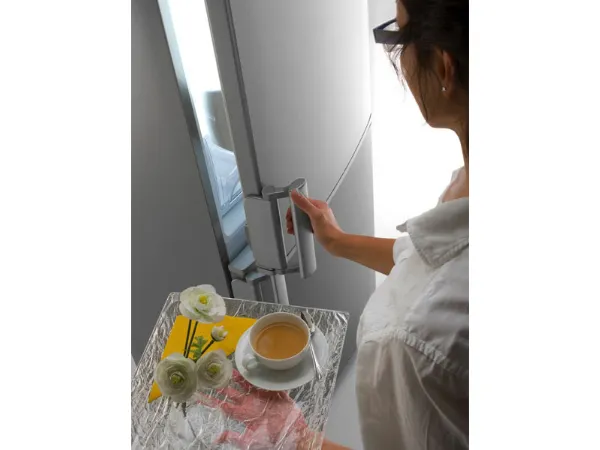 donna con vassoio con tè e fiori apre l'anta superiore del frigo 