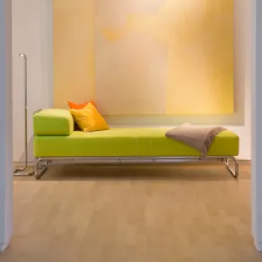divano chaise-longue verde mela, cuscini giallo e arancio, coperta ecrù, quadro astratto giallo