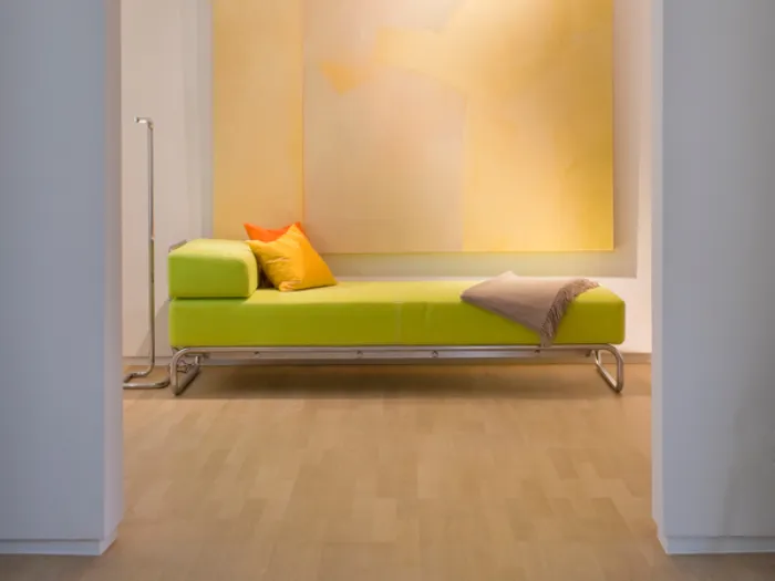 divano chaise-longue verde mela, cuscini giallo e arancio, coperta ecrù, quadro astratto giallo