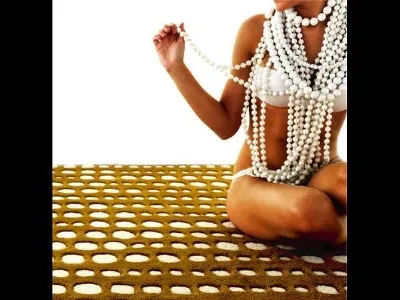 donna in bikini con collana a multipil giri di perle su tappeto con fori circolari