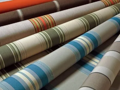 Rotoli di tessuti a righe blue, verde, arancio su sfondi naturali