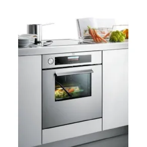 forno in acciaio in mobile cucina, ricettario e verdure